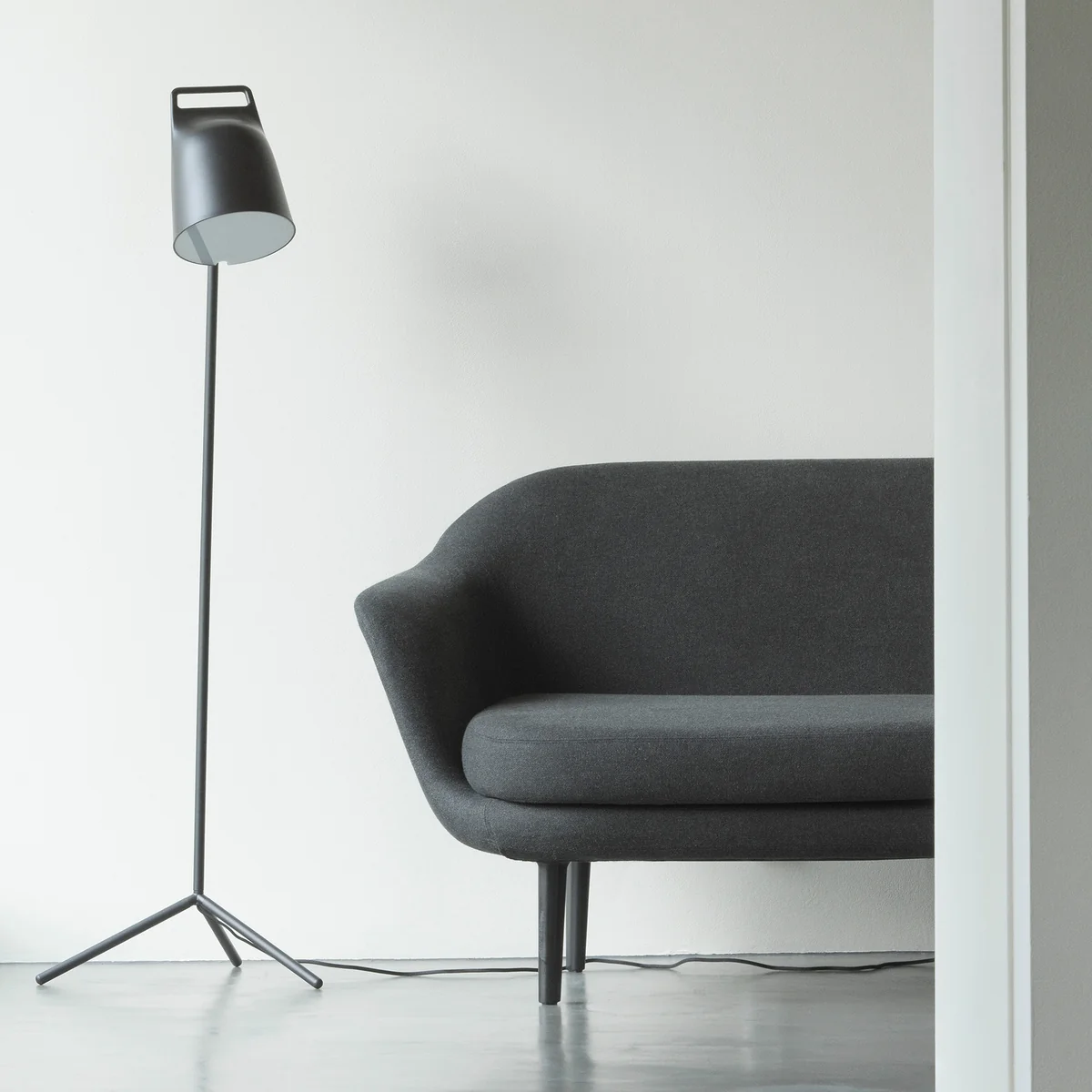 The Stage LED floor lamp from Normann Copenhagen next to a grey couch