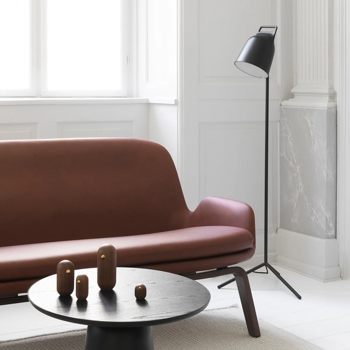 The Stage LED floor lamp from Normann Copenhagen next to a brown leather couch