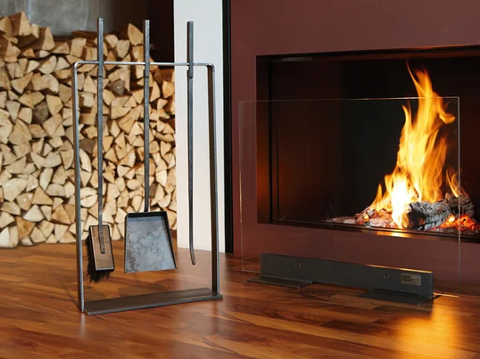 With the helping hands fireplace tools by artepuro, long-handled poker rakes, brooms and shovels line up on a narrow steel frame made of oiled black steel.