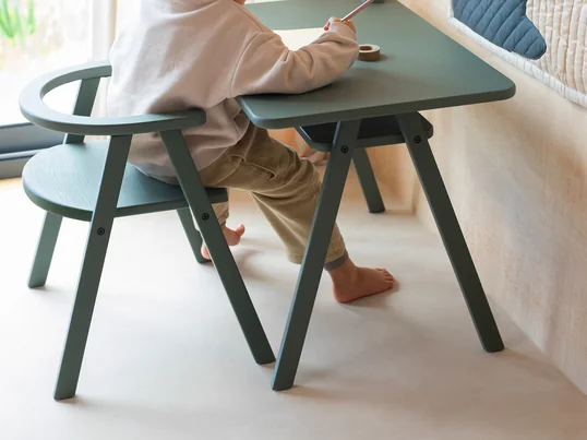 The red children's chair, designed by Arne Jacobsen, is light, stackable and available in beech in addition to other lacquer colours. The seat height of the four-legged chair is adjusted to children's size.