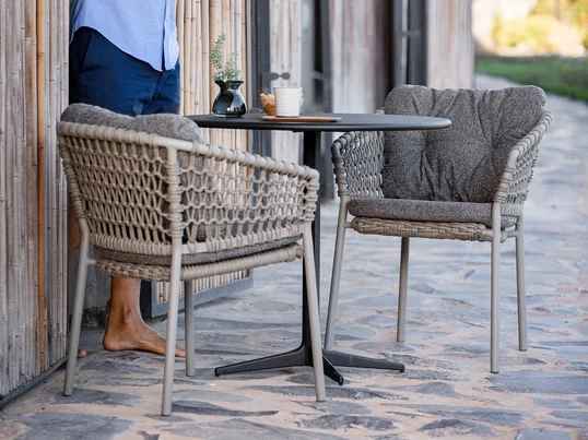 Ocean Armchair, taupe from Cane-line in the ambience view. A curved backrest and armrests offer pleasant comfort so that you can spend cozy hours in the chair.