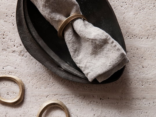 Lifestyle product image of the decorative Flow napkin rings made of brass in a practical set of 4 and the Forest decorative tray made of brass in black from Ferm Living.