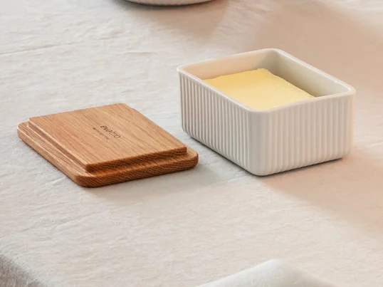 The chic Legio Nova butter dish by Eva Trio in oak consists of a lid made of oak wood and a bowl made of fine porcelain with a grooved pattern. The piece of butter can be stored in the porcelain bowl and closed with the wooden lid.
