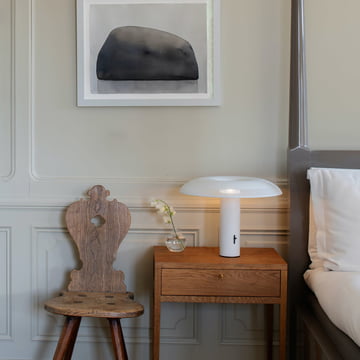 The w203 Ilumina LED table lamp by Wästberg on a classic wooden bedside table next to a grey bed