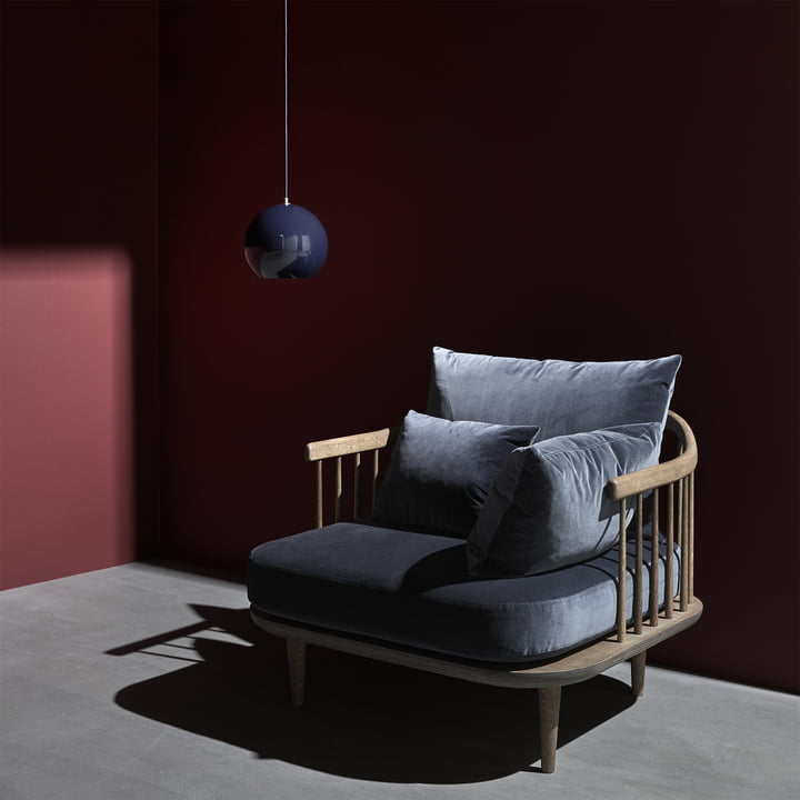 The Topan pendant lamp VP6 from & Tradition over a gray armchair with wooden frame