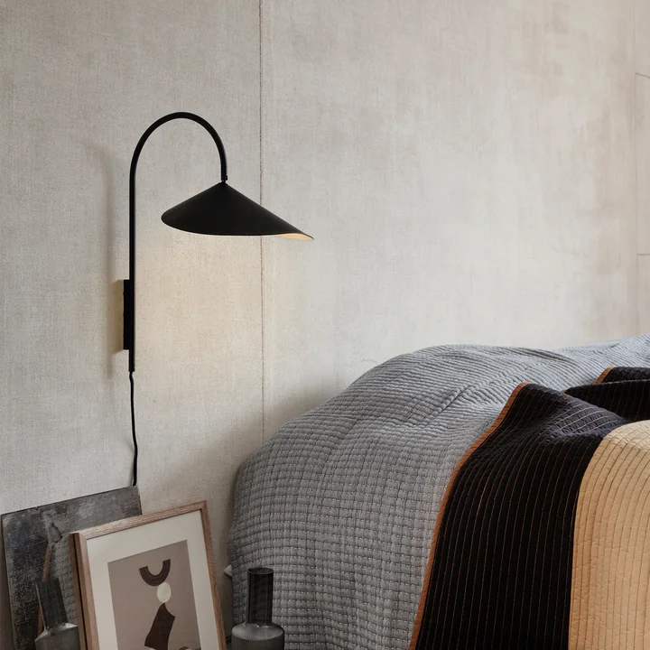 Arum Wall lamp in black from Ferm Living next to the bed