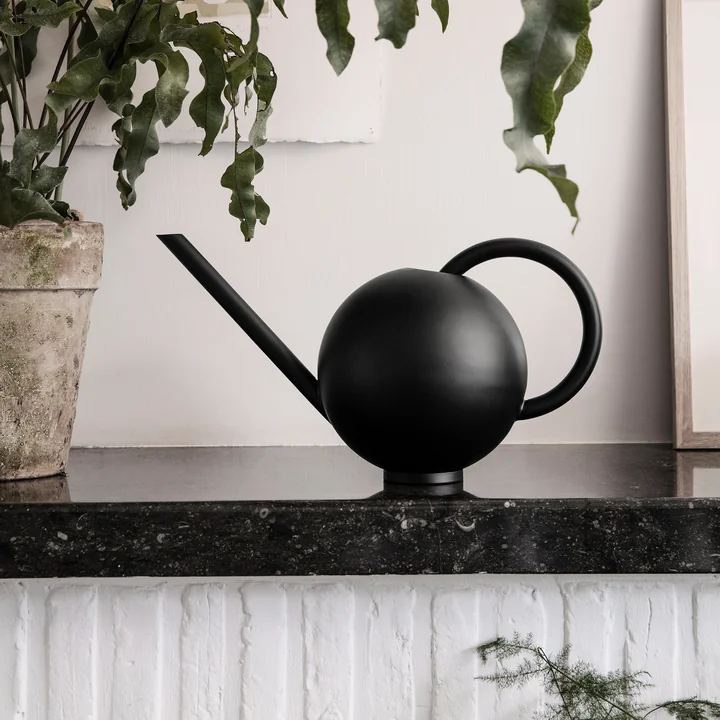 Orb watering can from Ferm Living next to a plant