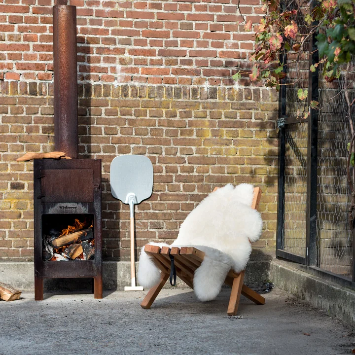 Fieldchair with sheepskin and the outdoor steel stove from Weltevree on the terrace