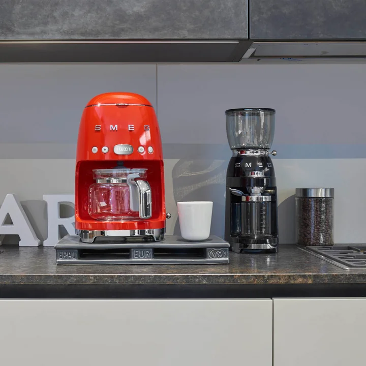 Coffee grinder in black and coffee machine in red from Smeg