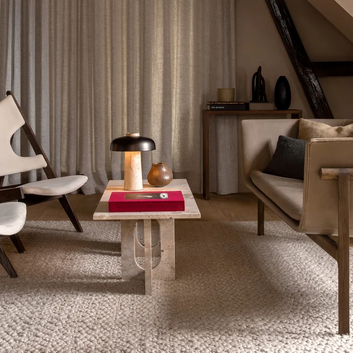 The Androgyne lounge table from Audo as a coffee table between the sofa and lounge chairs in natural colors