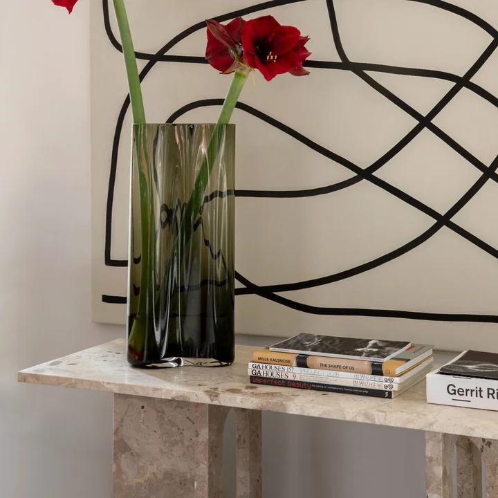 The Androgyne Lounge Table from Audo in combination with a large artwork on the wall, a vase and books