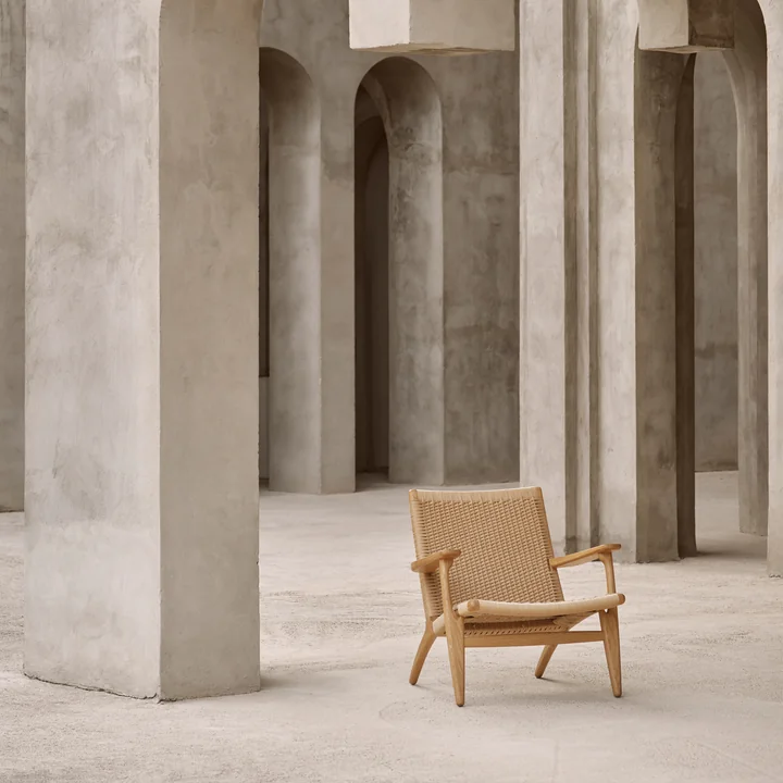 The comfortable CH25 armchair from Carl Hansen in the middle of stone walls
