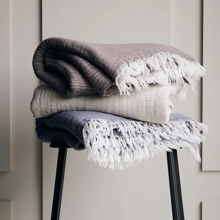 Alice blanket by House Doctor stacked on a stool in an ensemble