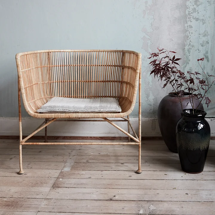The Cuun Rattan Lounge Chair, natural by House Doctor in the living room next to house plants