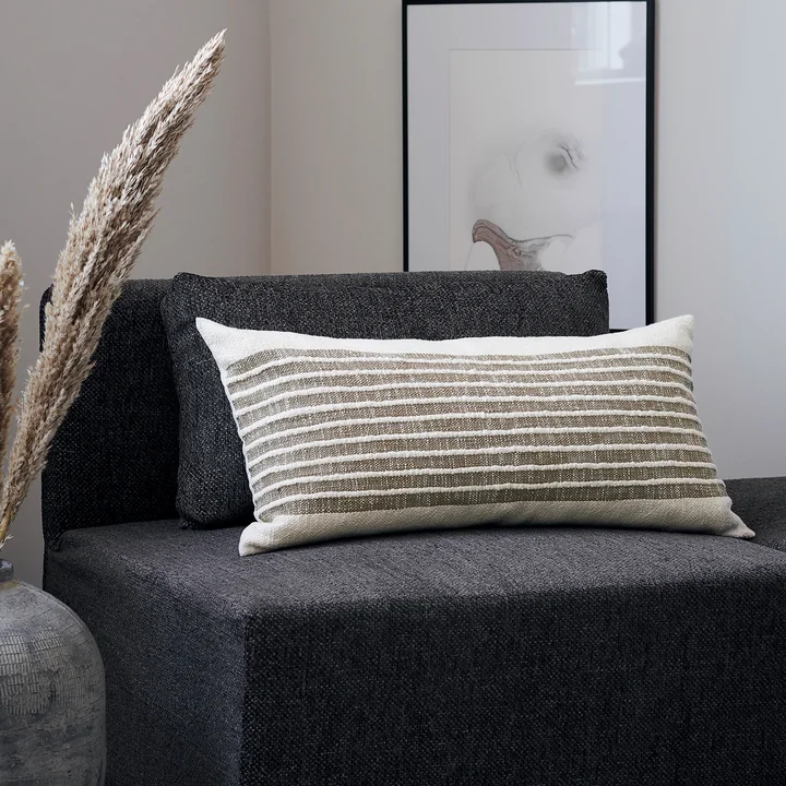 The Yarn pillowcase, mustard yellow by House Doctor on a dark armchair