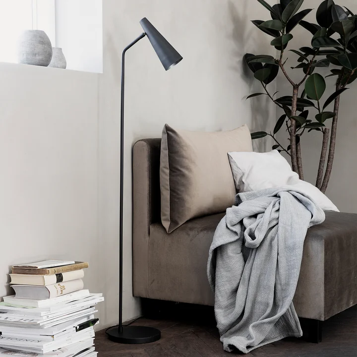 The floor lamp Precise, matt black by House Doctor next to the armchair in the living room