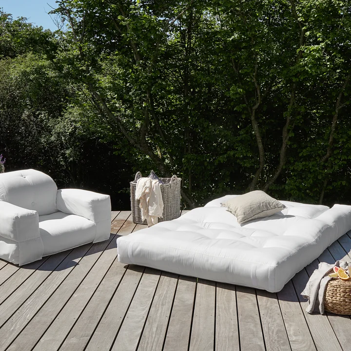 The Hippo OUT products from Karup Design on a wooden terrace surrounded by trees and bushes