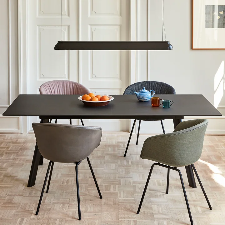 The PC Linear rod pendant lamp, soft black from HAY above a black rectangular dining table