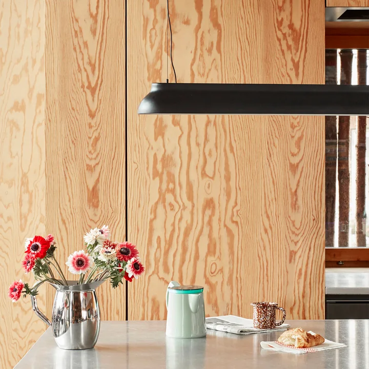 The PC Linear rod pendant light, soft black from HAY above the bright kitchen island