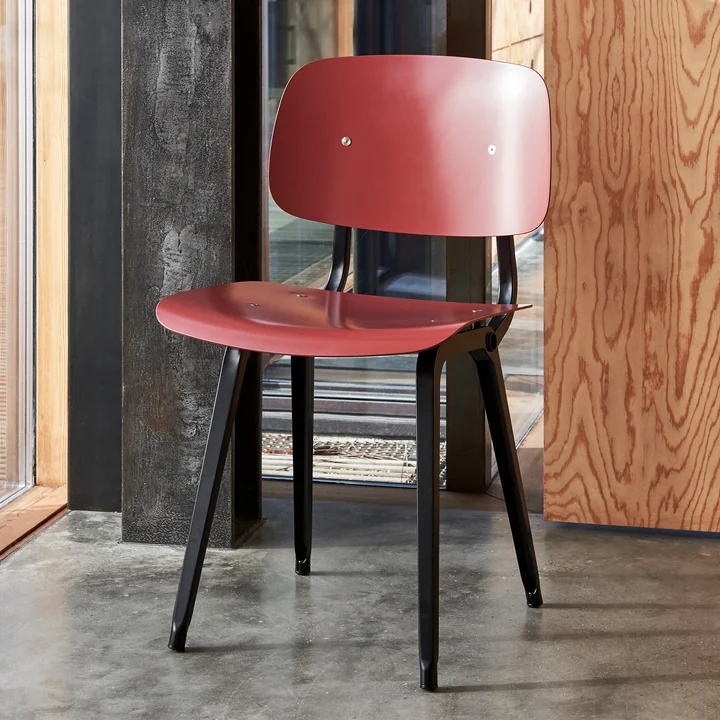 The Revolt Chair, black / plum red by HAY in a room with lots of wood and stone