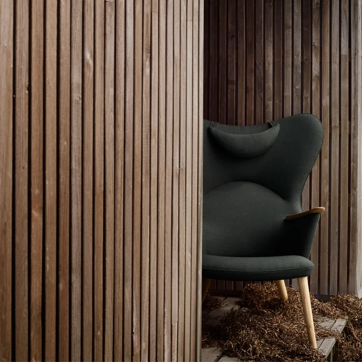 The CH78 Mama Bear Lounge Chair of Carl Hansen between rustic wooden walls