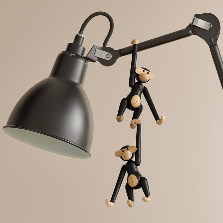 The mini wooden monkey, stained black oak by Kay Bojesen on the arm of a table lamp