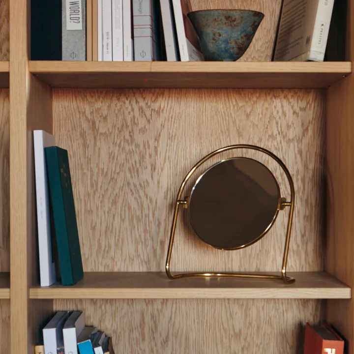The Nimbus table mirror, brass gold from Audo in a wall shelf