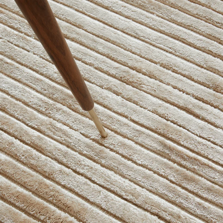 The Houkime carpet, beige from Audo is characterized by a ribbed pattern