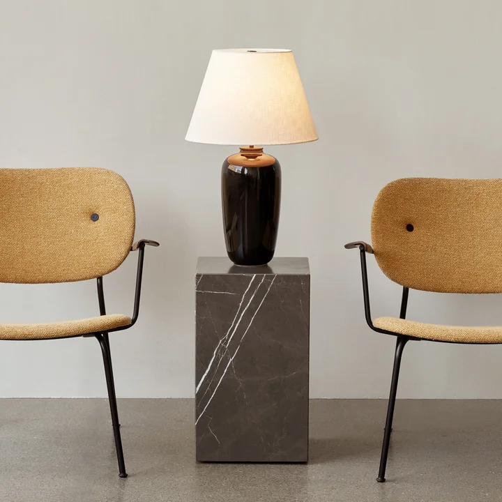 The switched-on Torso table lamp, black / off white from Audo on a side table next to chairs