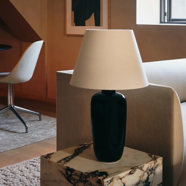 The Torso table lamp, black / off white from Audo on a side table next to the couch
