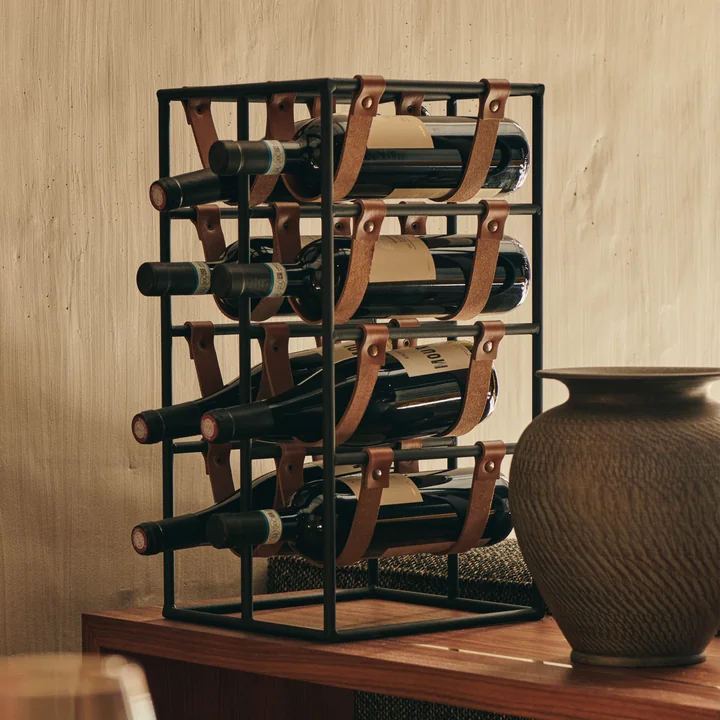 The Umanoff wine rack for 8 bottles, steel black (RAL 9005) / leather brown from Audo on a wooden counter