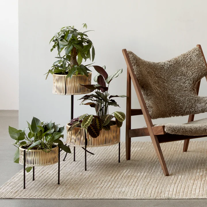 The Umanoff plant pots, rattan / black in combination with the Knitting Chair, walnut / Sheepskin Cork 19 and the Houkime carpet, beige from Audo .