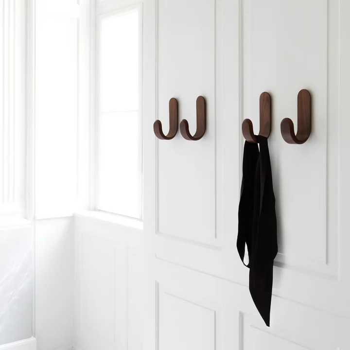 The Curve Walnut wall hook from Normann Copenhagen on a white wooden wall