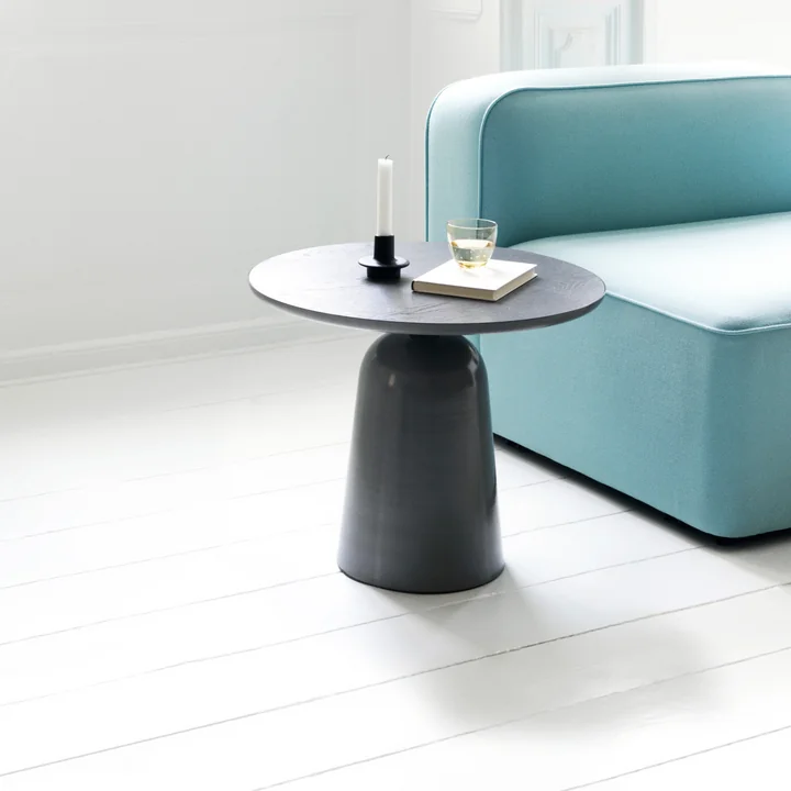 The Turn coffee table from Normann Copenhagen next to a turquoise couch