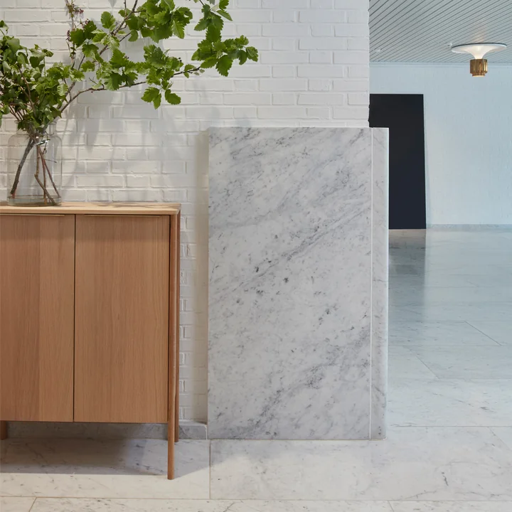 The Jut High Cabinet from Skagerak in the hallway with white marble floors and walls