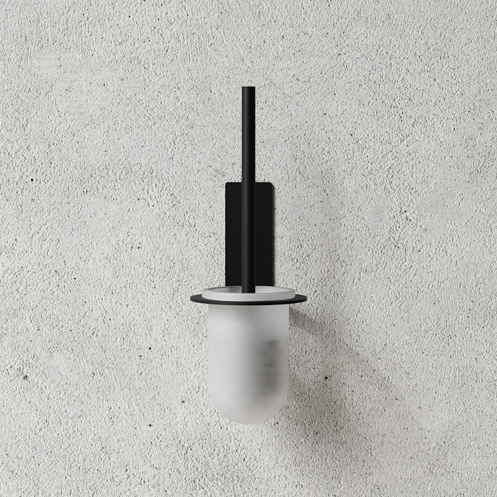 The toilet brush with wall mount from Nichba Design on a stone wall