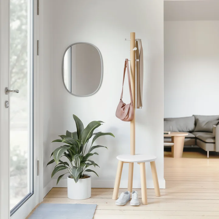 The Pillar stool / coat stand from Umbra in the bright hallway next to a wall mirror and a large potted plant