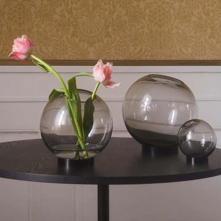 The Globe vase of AYTM in its different sizes on a black side table