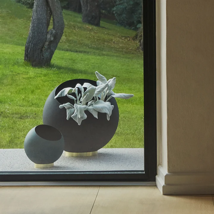 The Globe flowerpot of AYTM in its various sizes behind a floor-to-ceiling window in the open
