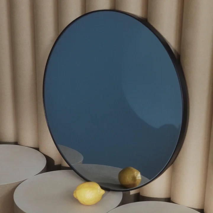 The Circum wall mirror from AYTM leaning against a corrugated metal wall