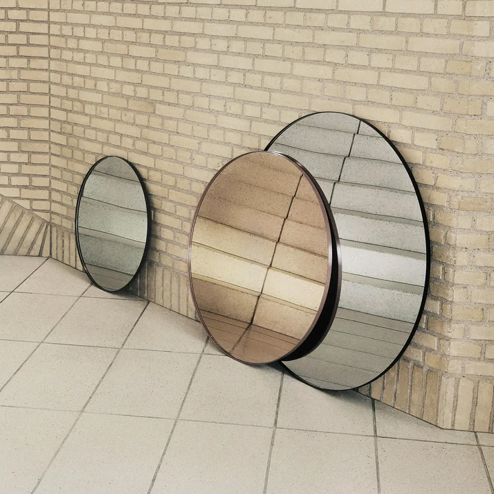 The Circum wall mirror from AYTM in its various sizes leaning against a wall