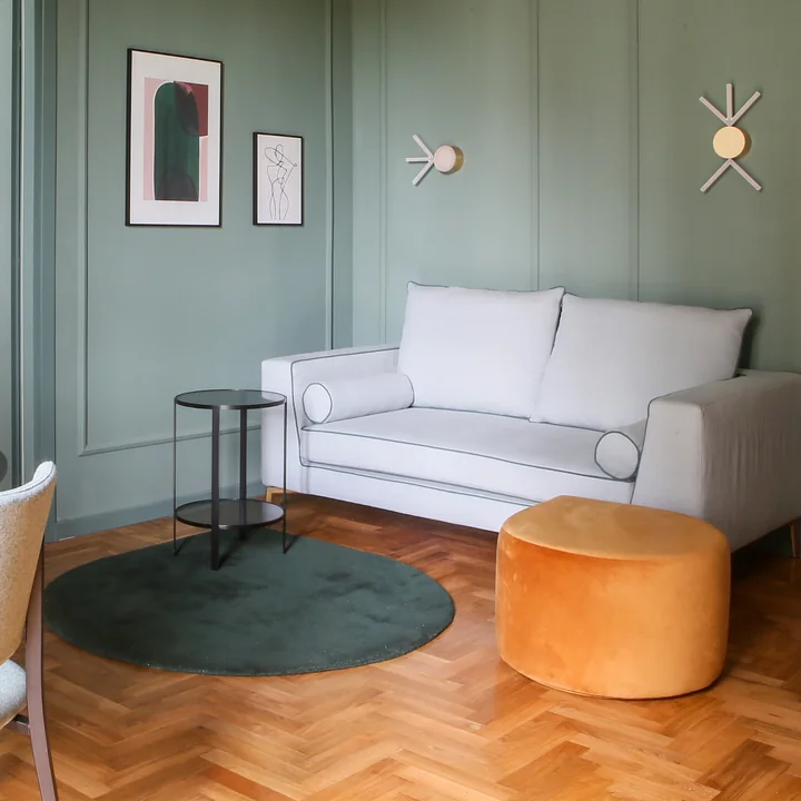 The Stilla rug of in AYTM the colorful living room with green walls and wooden parquet floor