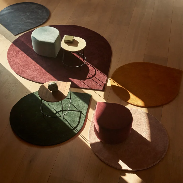 The Stilla rug from AYTM in its various sizes and colors with side tables and poufs