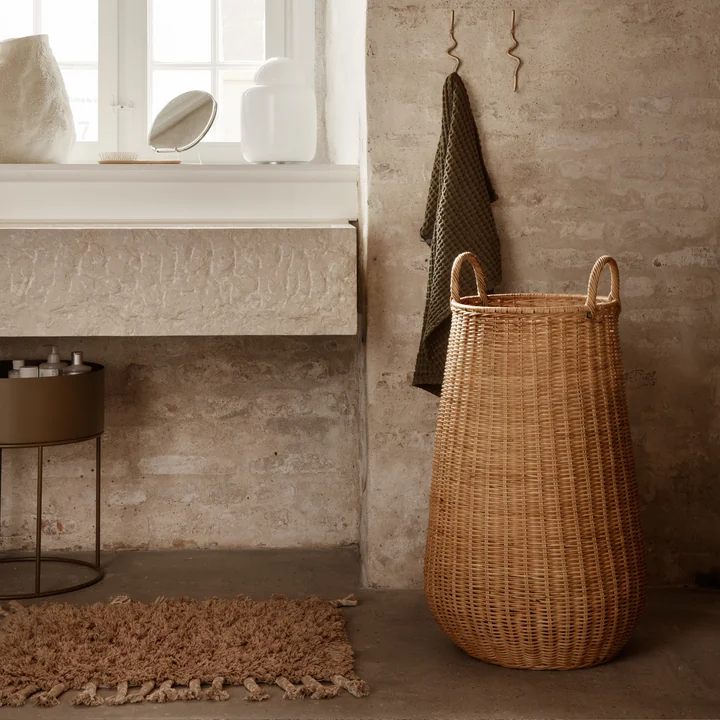 The Amass high-pile doormat from Ferm Living under the washbasin next to a rattan basket