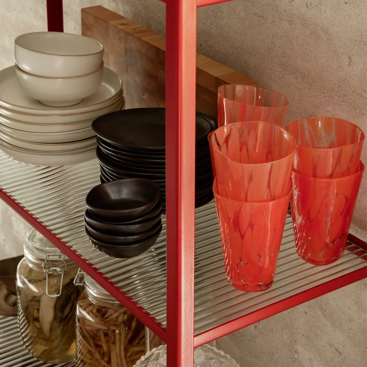 The Casca drinking glass from Ferm Living in poppy red on a wall shelf next to other tableware