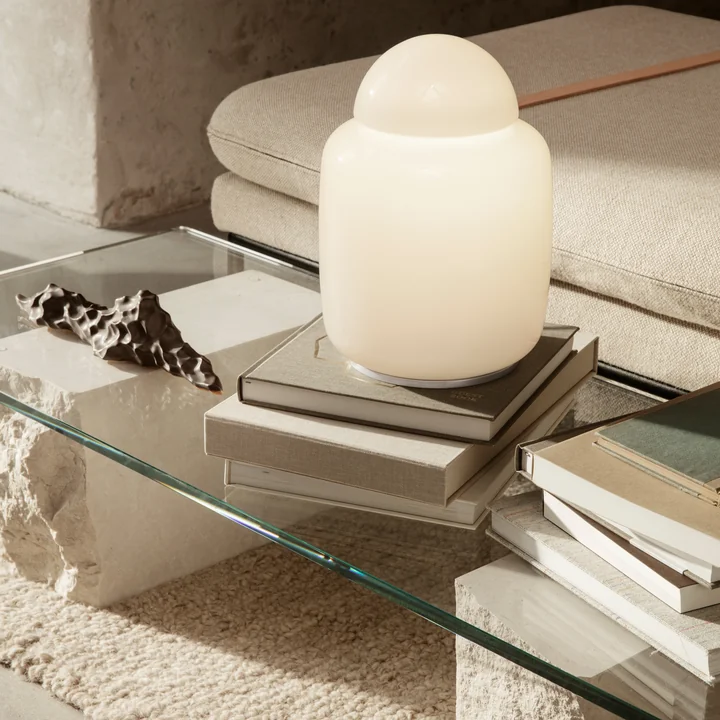 The Bell table lamp from Ferm Living on stacks of books on a glass coffee table