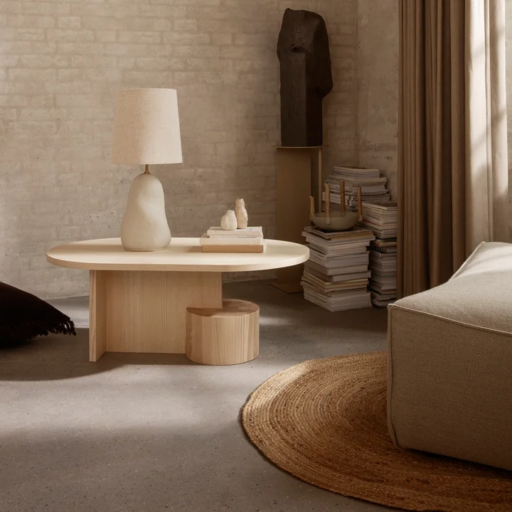 The Eternal oval jute carpet by Ferm Living under a couch and next to a wooden coffee table