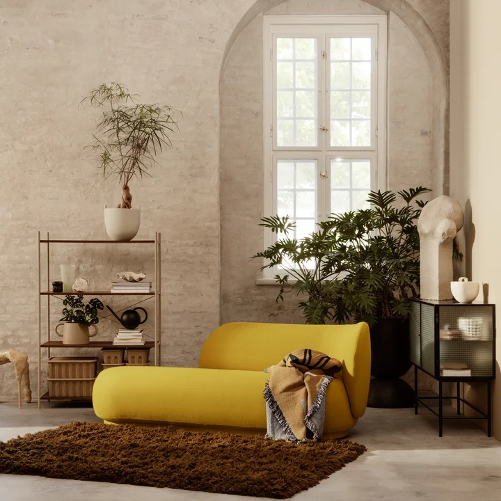 The Meadow high pile carpet in front of a yellow couch in a living area with high stone walls