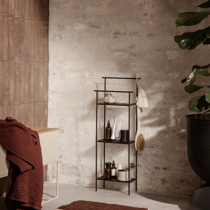 The Dora bathroom shelf by Ferm Living with bathroom accessories next to a large houseplant