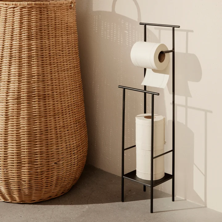 The Dora toilet roll holder from Ferm Living next to a large rattan basket